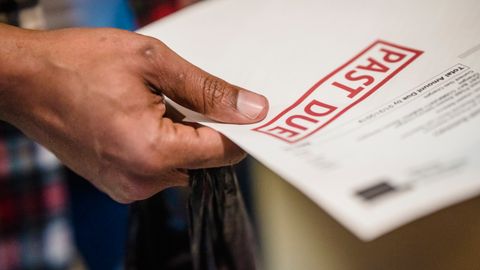 A close-up of a hand holding a document with a 'Past Due' stamp, highlighting financial urgency.