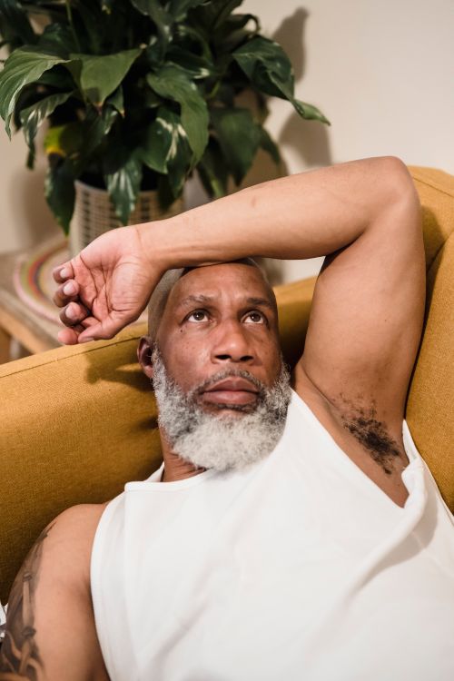 Free Portrait of a relaxed, bearded African American man lying on a couch at home. Stock Photo