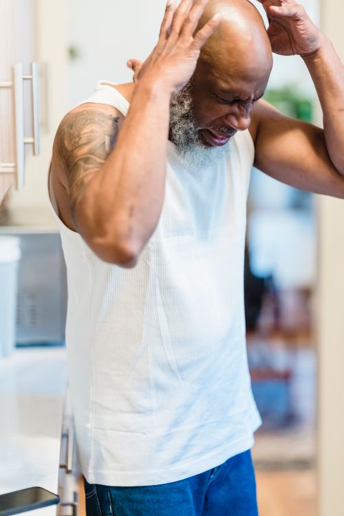 Free An adult man showing emotions in a home setting, wearing a tank top. Stock Photo