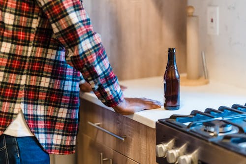 Person in Red Black and White Plaid Dress Shirt Standing beside Brown Wooden Counter