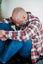 Man in Red White and Black Plaid Dress Shirt and Blue Denim Jeans Sitting on Chair