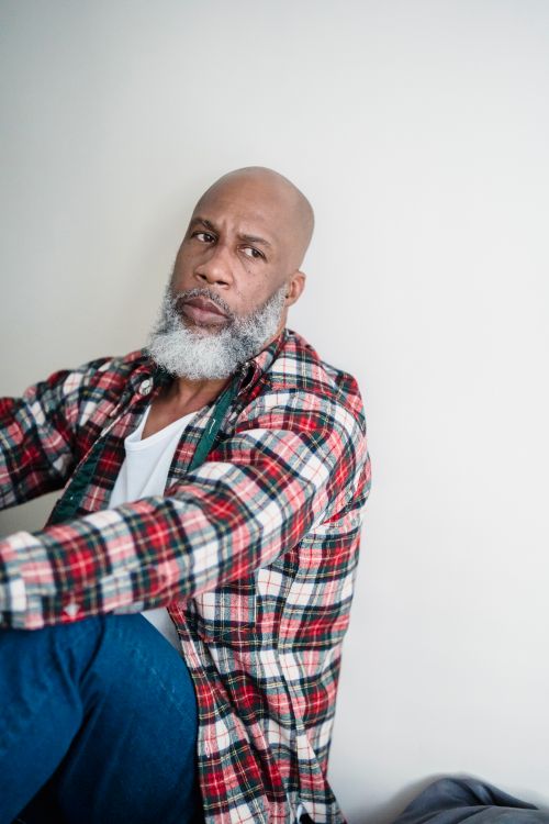 Free Thoughtful man with a beard in a plaid shirt sitting against a white wall. Stock Photo