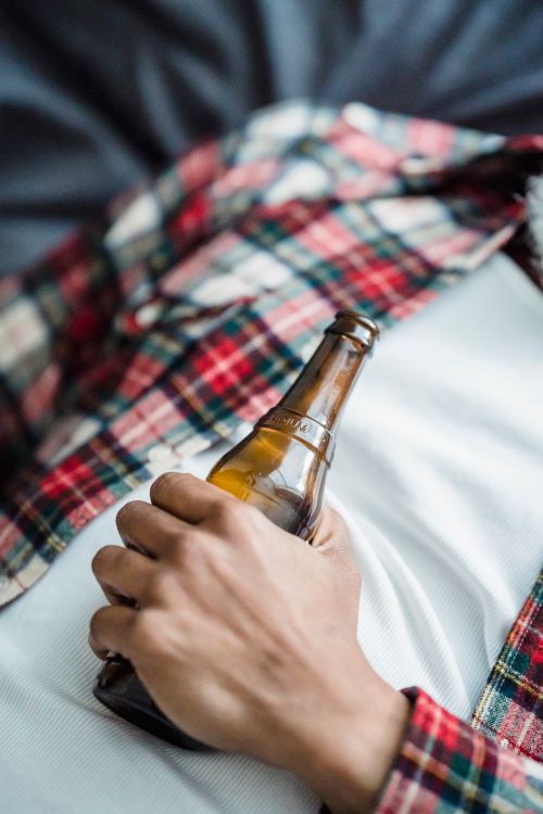 Free A person in casual attire holds an amber beer bottle close up, evoking a relaxed vibe. Stock Photo