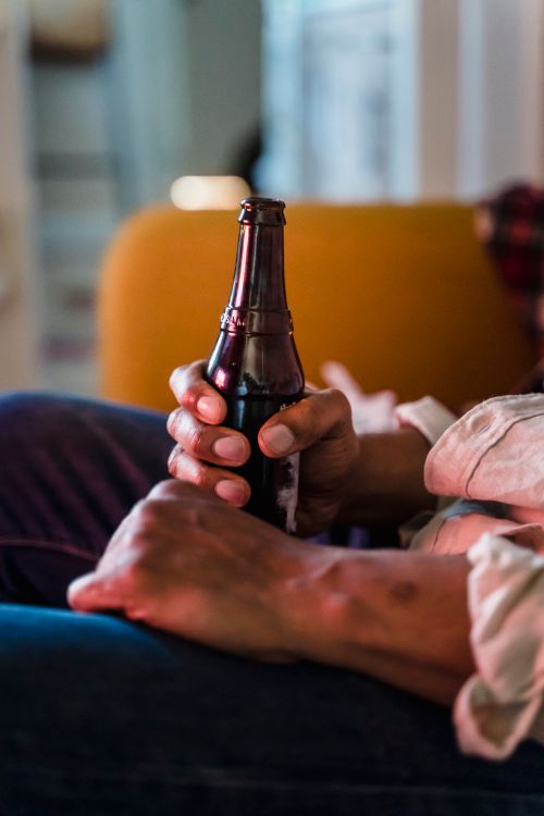 Free Close-up of a person holding a dark glass bottle, suggesting leisure. Stock Photo
