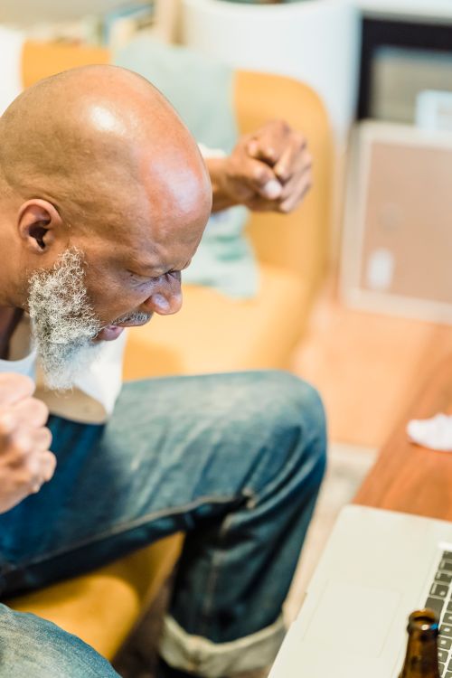 Free Stressed man gesturing with clenched fists while sitting indoors. Emotional and intense moment. Stock Photo