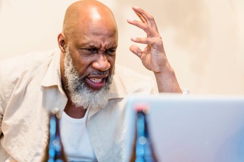 Free An adult man expressing frustration during a video call with a laptop indoors. Stock Photo