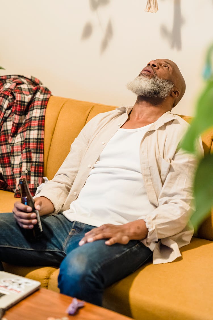 Old Man Sitting On Couch Drinking Beer