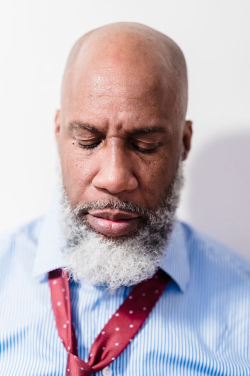 Free Close-up portrait of a bald man with a grey beard wearing a blue striped shirt and red tie. Stock Photo