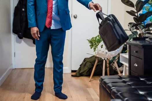 Man in Blue Suit Jacket and Blue Pants Holding Black Leather Sling Bag