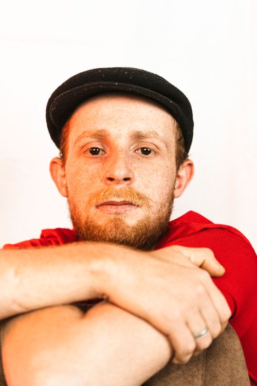 Free A close-up studio portrait of a bearded man in a red shirt and beret. Stock Photo