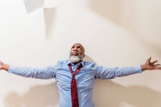 A frustrated businessman with arms outstretched, expressing vulnerability and stress indoors.