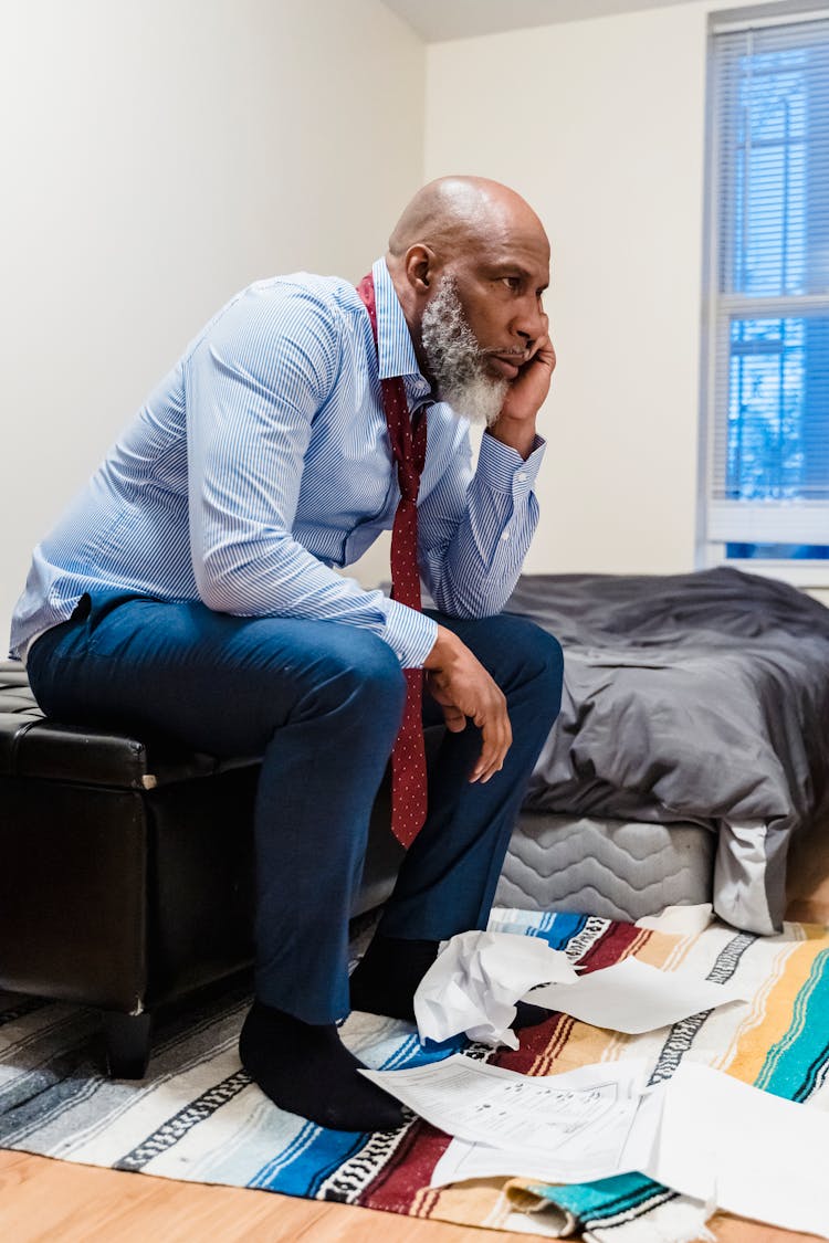 Stressed Old Man Sitting With Scattered Papers