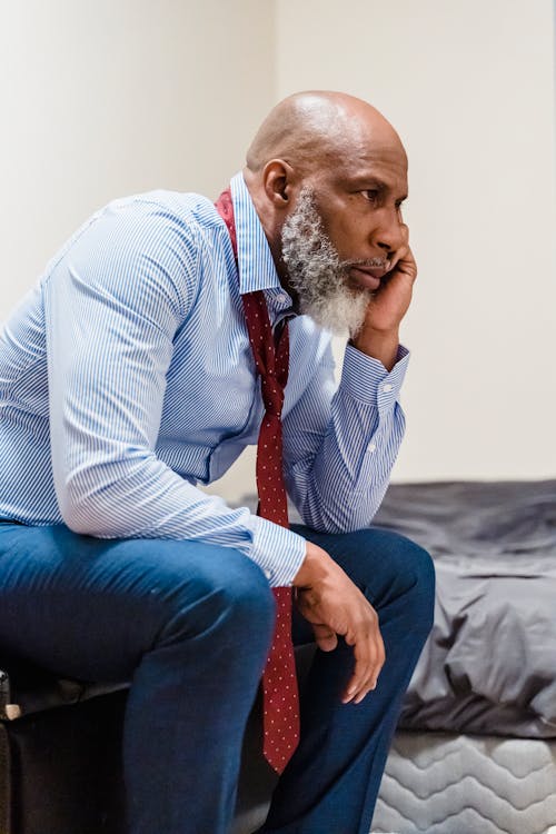 Unhappy Old Man in Suit Sitting Outdoors Thinking