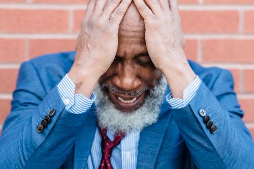 Free Close-up of a stressed African American man with a beard holding his head, expressing anxiety. Stock Photo
