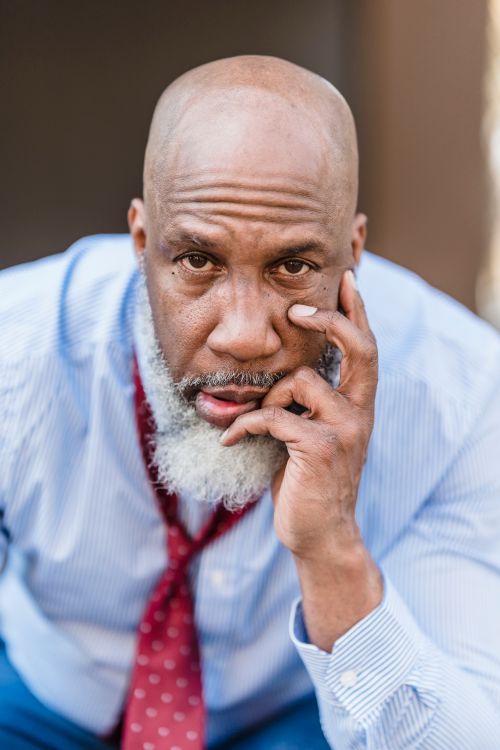 Free Portrait of a mature man with a gray beard in a shirt and tie, looking contemplative. Stock Photo