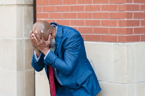 Free Man in Blue Coat Leaning on a Wall Stock Photo