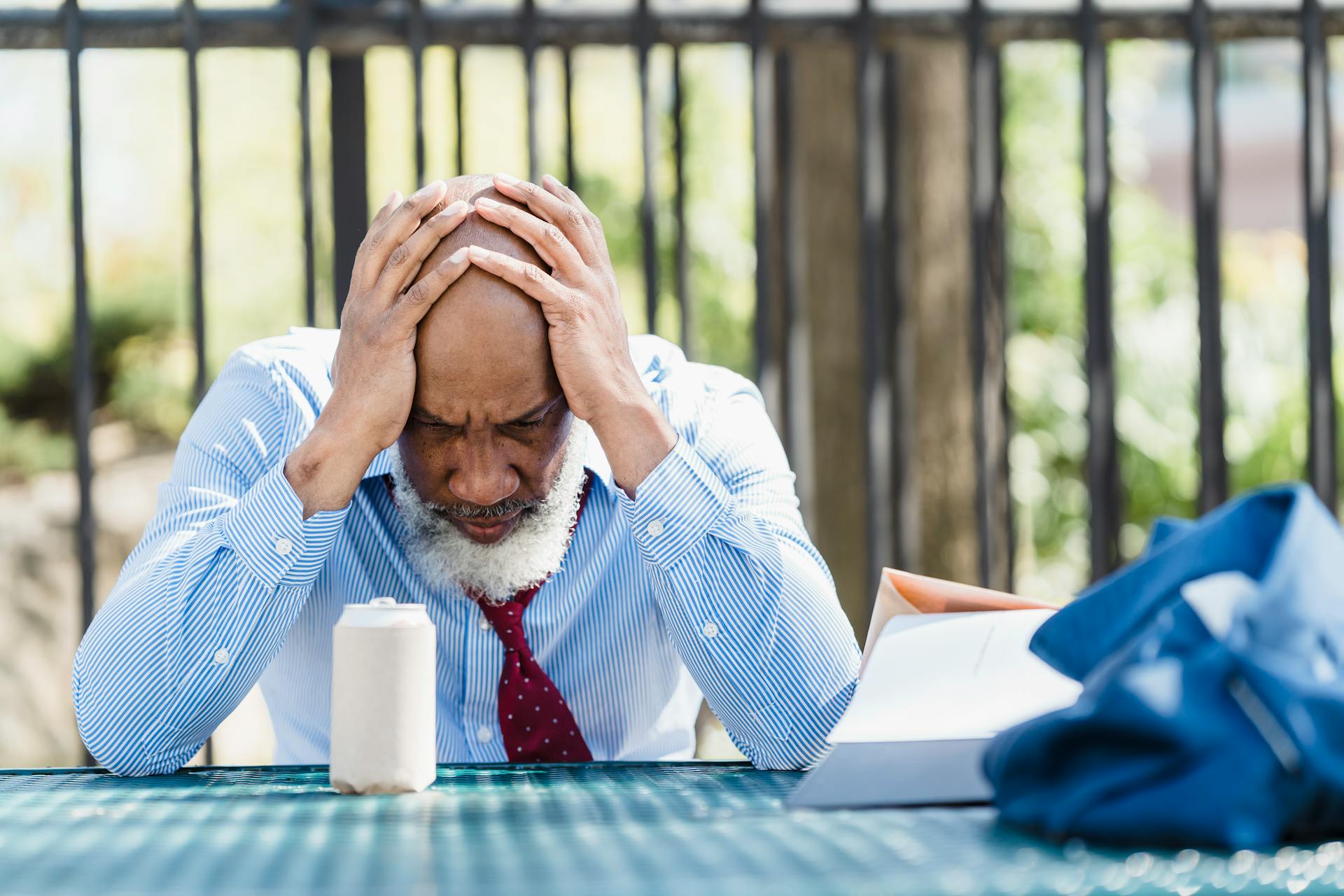 Mature man looking troubled while sitting outdoors, related to business stress.