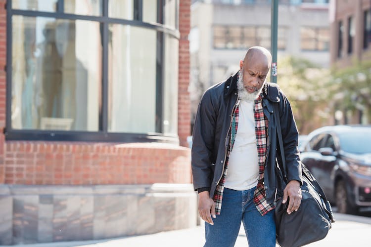 Unhappy Old Man With Bag Walking On Street