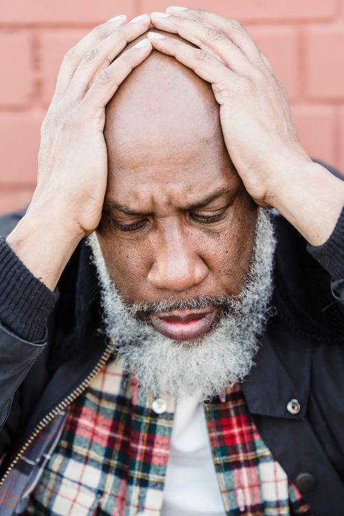 Free Close-up of a pensive man with facial hair looking stressed while sitting outdoors. Stock Photo