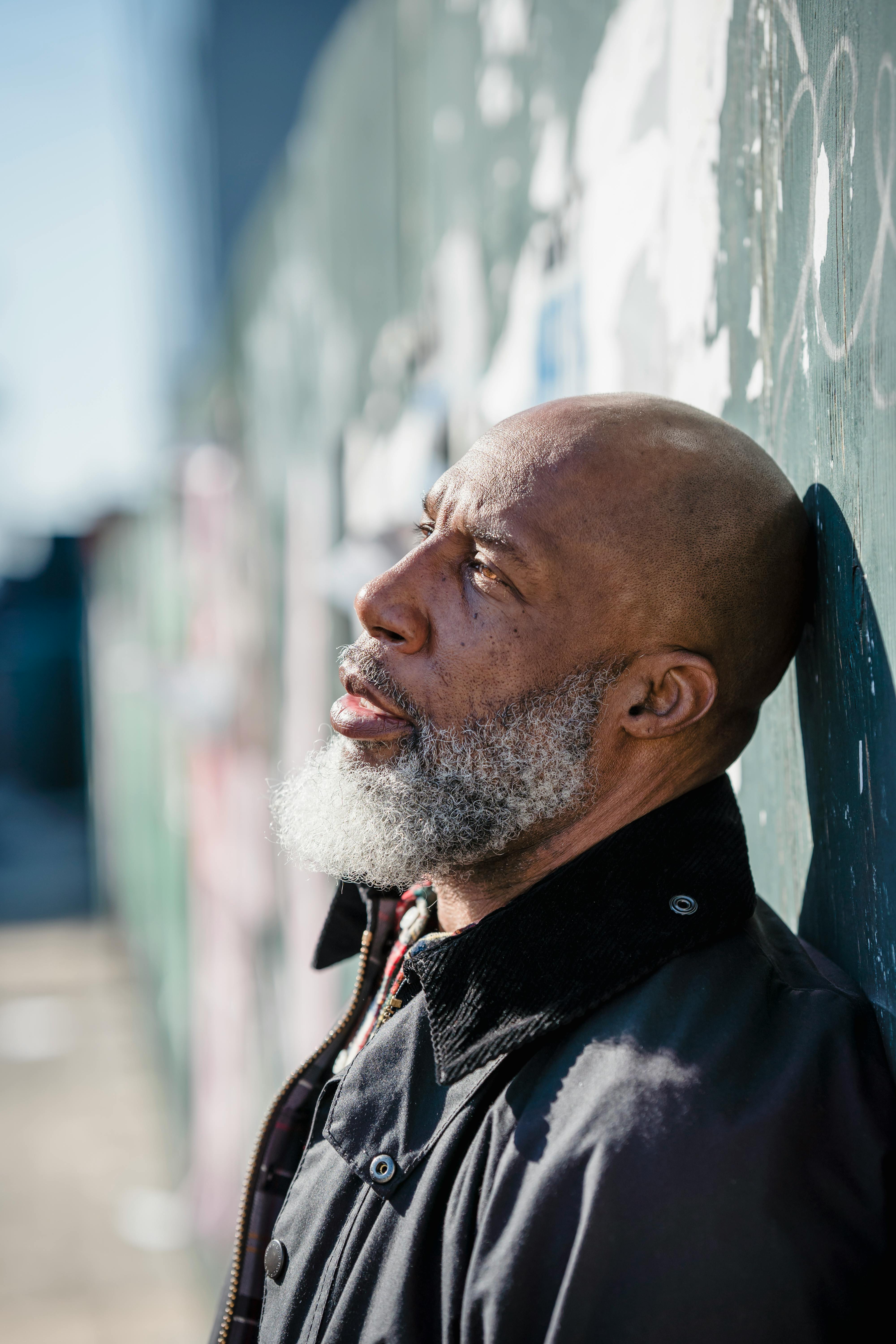 old bearded man standing near wall outdoors