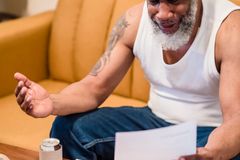 An African American man showing distress over unpaid bills, highlighting financial struggles.