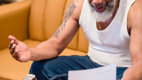 An African American man showing distress over unpaid bills, highlighting financial struggles.