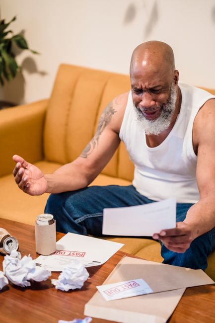 An African American man showing distress over unpaid bills, highlighting financial struggles. An African American man showing distress over unpaid bills, highlighting financial struggles.
