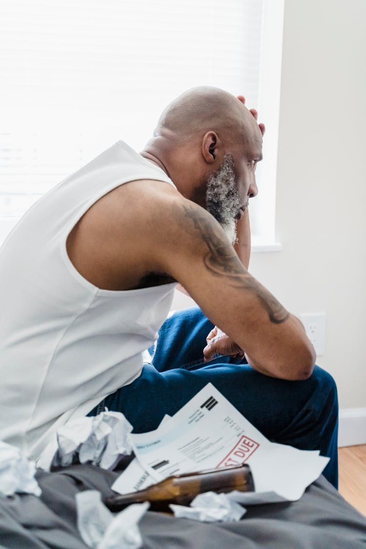 Stressed Man With Past Due Notices And Beer Bottles