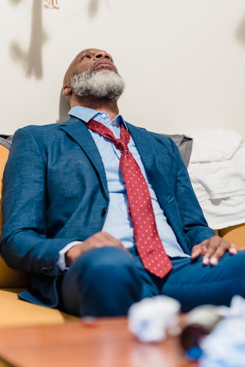 Free Man Wearing Blue Suit Sitting on a Couch Stock Photo
