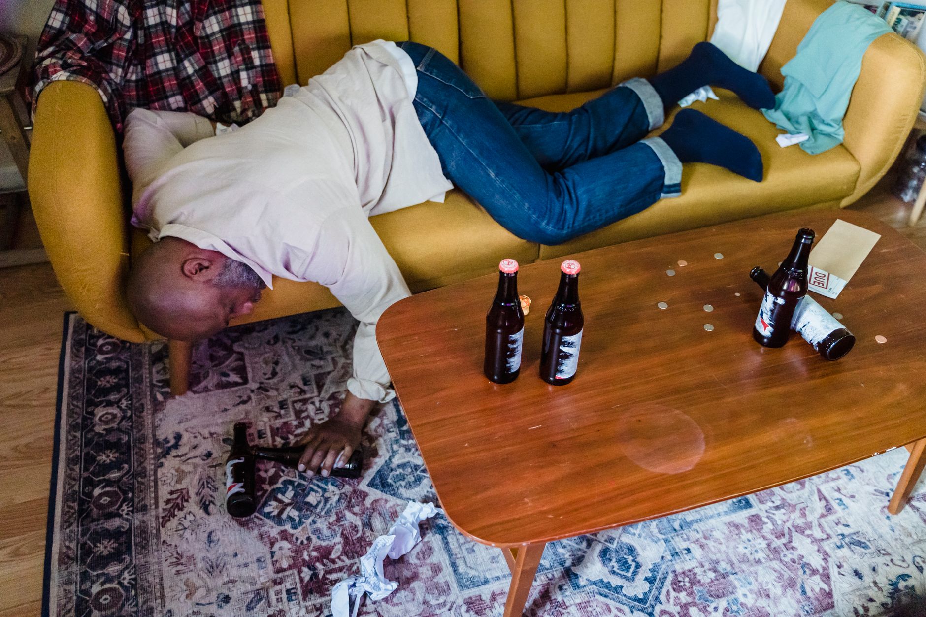 睡不著怎麼辦?睡前這些禁忌你踩雷了沒 A man asleep on a mustard yellow sofa surrounded by beer bottles indoors.