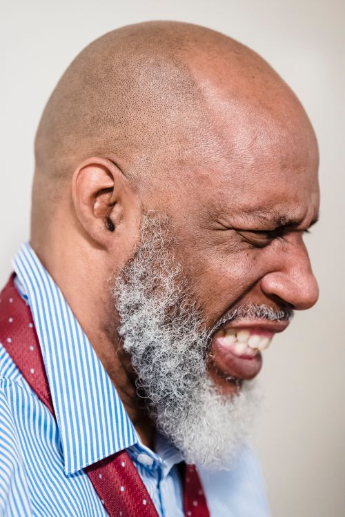 Free Profile view of a bald man with a beard expressing strong emotion indoors. Stock Photo