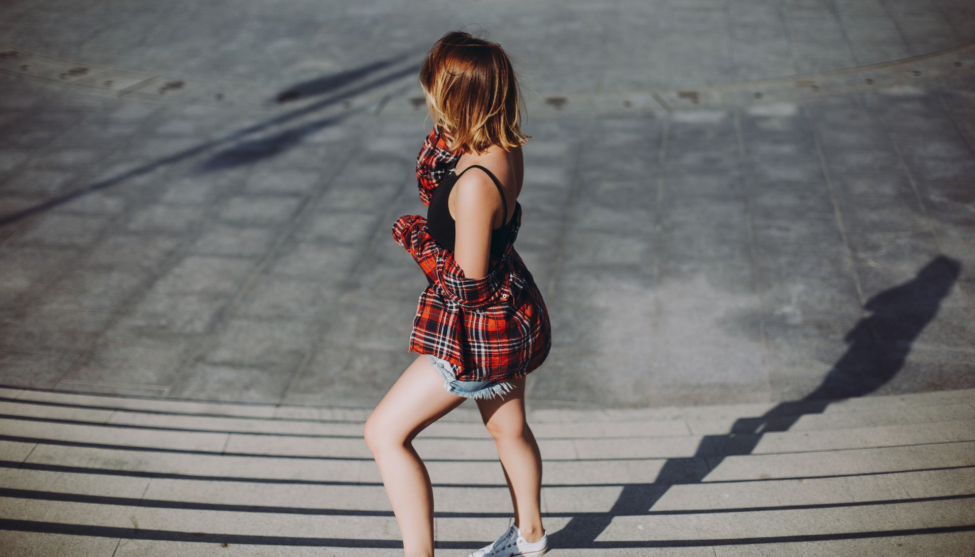 Young woman posing fashionably on sunlit steps in Baku, Azerbaijan.