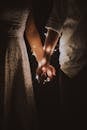 Man and Woman Holding Each Others Hand Wrapped With String Lights