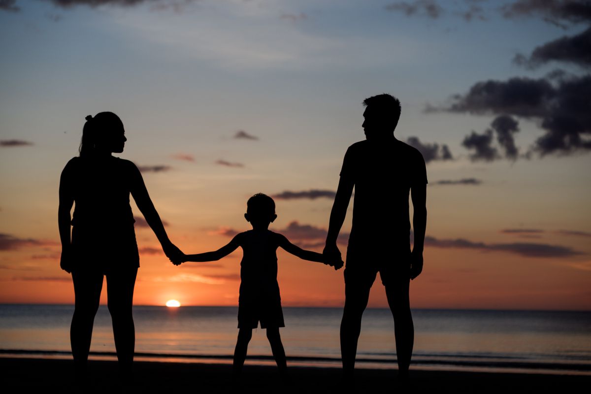A family holding hands on the beach at sunset