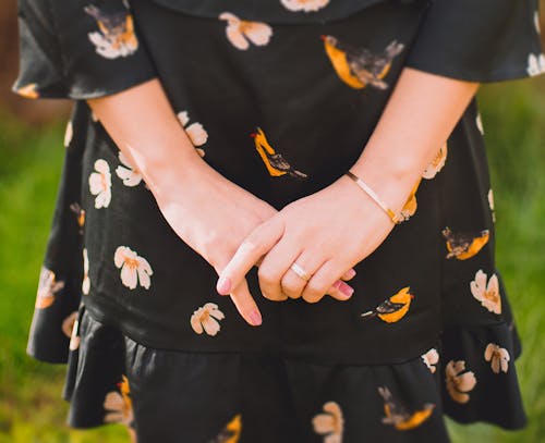 Close Up Photo of Person Wearing Black and Orange Floral Dress