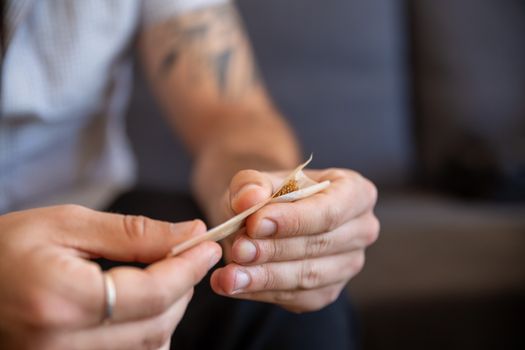 A detailed view of hands skillfully shaping a marijuana joint using rolling paper.