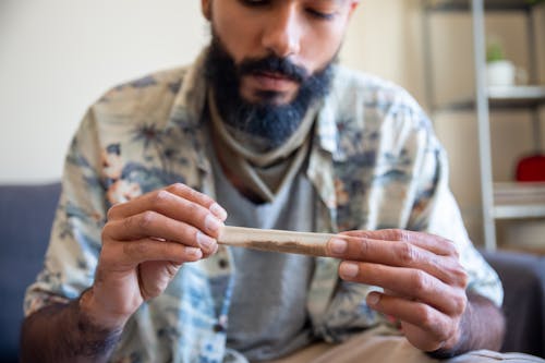 Man Wearing Hawaiian Shirt Holding a Rolling Paper with Cannibis