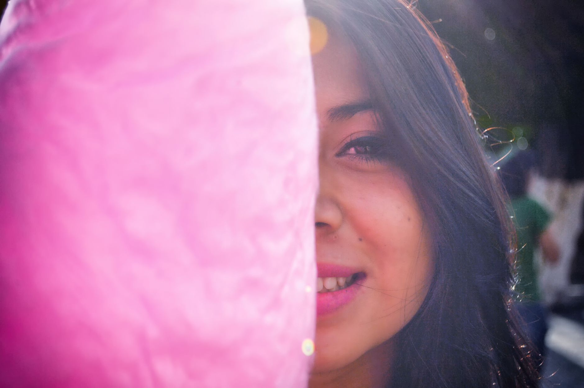 cotton candy machine rental cairo — Close-up of a smiling young woman partially hidden by pink cotton candy outdoors.