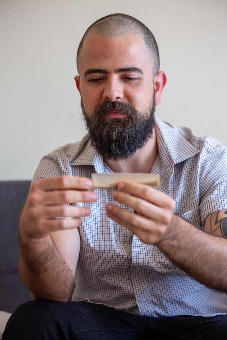 A Bearded Man Rolling A Blunt