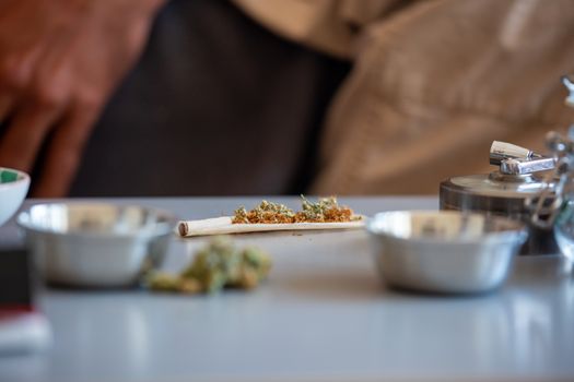 Detailed close-up of cannabis being rolled into a joint on a table with craft supplies.