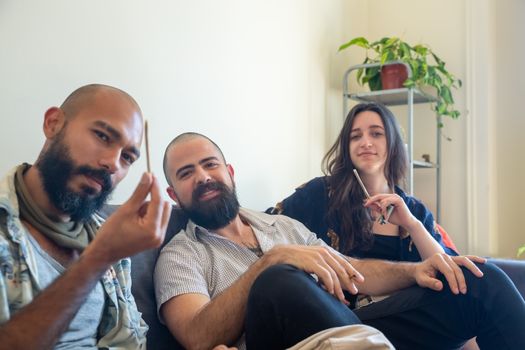 Three friends sitting on a couch together, enjoying each other's company indoors.