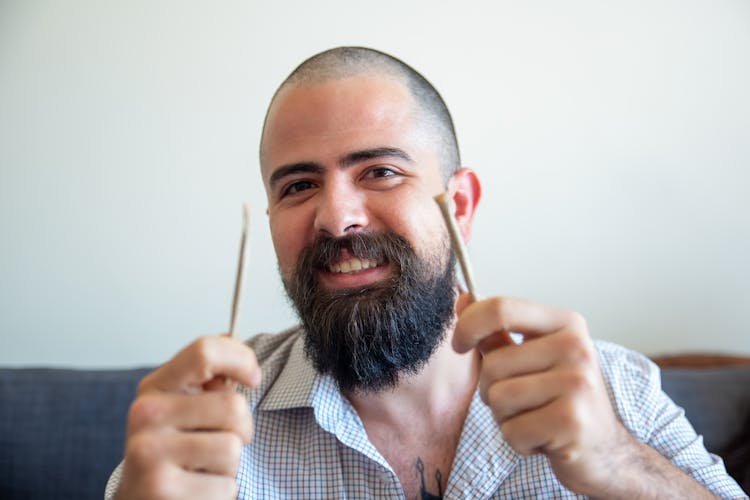 A Man Holding A Stick And A Joint