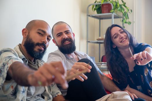 Three friends smiling and enjoying a relaxing moment indoors together.