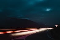 在黑暗、弯曲的高速公路上，夜间拍摄能捕捉到长曝光的光线轨迹