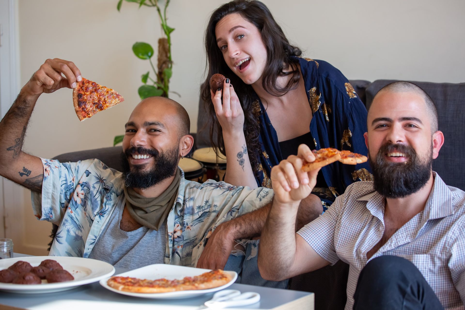 A joyful group of friends sharing pizza and snacks in a cozy indoor setting.