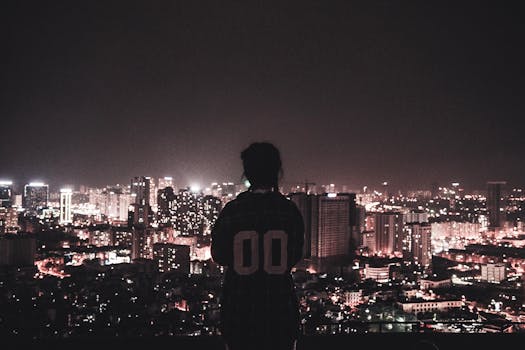 Silhouette of a person overlooking Hà Nội's city lights at night, showcasing the urban skyline.