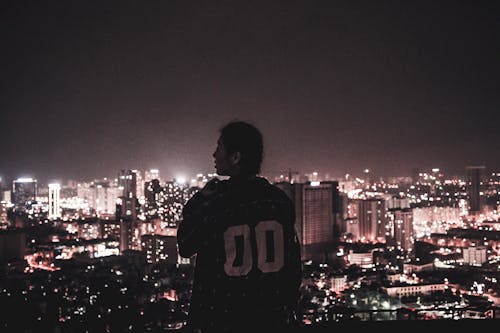 Fotografia De Uma Pessoa Observando As Luzes Da Cidade Durante A Noite