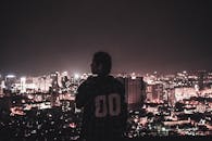 一个人凝视着河内的夜景，剪影捕捉着充满活力的城市天际线