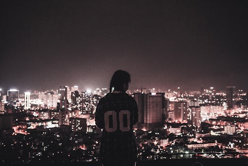 Фотография человека, наблюдающего за городскими огнями в ночное время