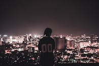 夜晚，一个人站在楼顶，凝望着越南河内明亮的天际线